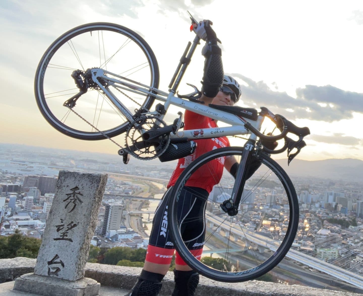 夕日を背にロードバイクを持ち上げるサイクリスト